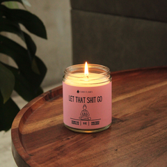 Candle in a glass jar with a pink label on a wooden surface