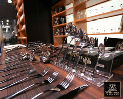 Silver cutlery set with Wilmax England packaging on a wooden surface.