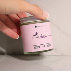 Hand holding a candle labeled 'just relax' with a pink label.