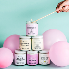 Stack of candles with humorous text on a light blue background with pink balloons.