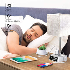 Man sleeping in bed with a nightstand lamp, tablet, and phone, featuring dual alarms, USB charging, and clock functions.