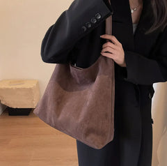 Person holding a brown suede handbag indoors