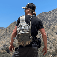 Person wearing a camouflage backpack in a mountainous landscape