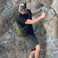 Person climbing a rocky mountain with a green backpack