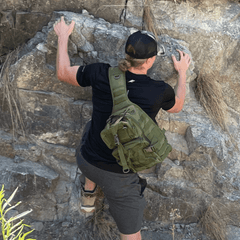 Person climbing a rocky wall with a green backpack