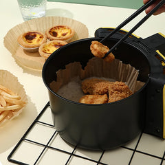 Person using tongs to remove fried chicken from a black deep fryer.