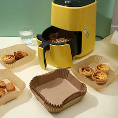 Yellow air fryer with food items on a white surface