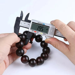 Digital caliper measuring a bracelet with dark wooden beads on a white background