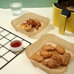 Fried chicken pieces in paper containers on a table with a glass of water and small bowl of sauce.