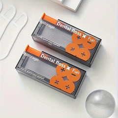 Two boxes of dental floss with orange and gray design on a white surface.