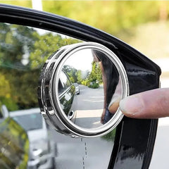 Round convex mirror attached to a car window with a blurred street scene in the background