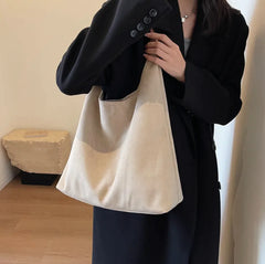 Person holding a beige tote bag against a neutral background