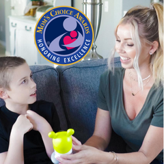Woman and child sitting on a couch with a product, featuring the Mom's Choice Awards logo.