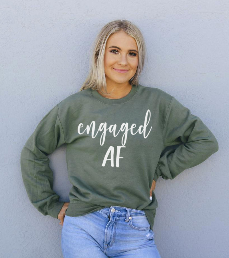 Woman wearing a green sweatshirt with 'engaged AF' text against a light gray background