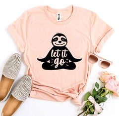 Pink t-shirt with sloth graphic and 'let it go' text, surrounded by shoes, sunglasses, and flowers on a white background.