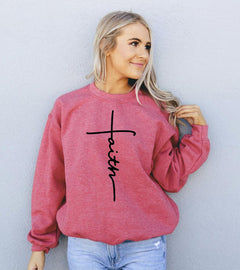 Woman wearing a scarlet red sweatshirt with 'Faith' printed on it against a light gray background