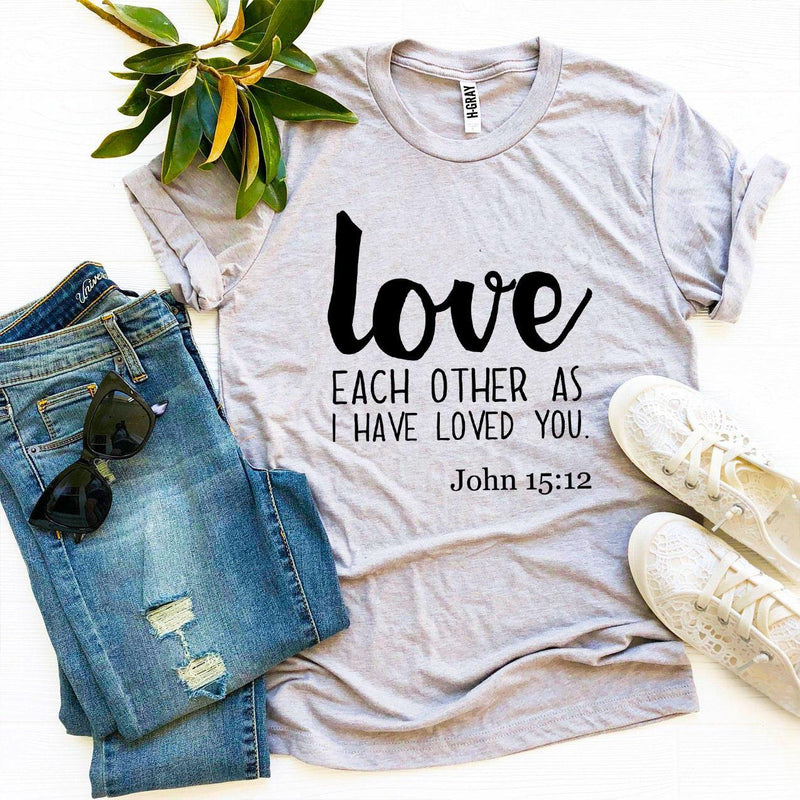 Gray t-shirt with 'love each other as I have loved you' text, paired with jeans and sneakers on a light background.