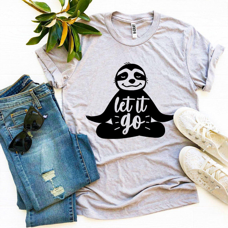 Gray t-shirt with sloth graphic and 'let it go' text, paired with jeans and sneakers on a white background.