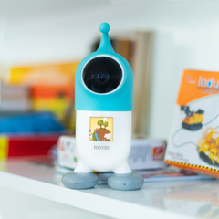 Blue and white robot toy with 'ROYBI' branding on a table with colorful background