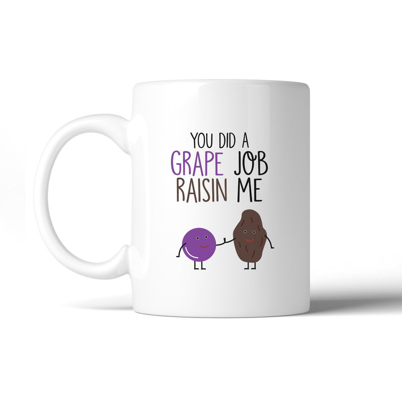 White mug with humorous design of a grape and raisin holding hands and text on a white background