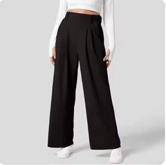 Black wide-leg pants worn with a white top on a light gray background