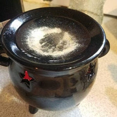 Black ceramic pot with star designs on a beige surface