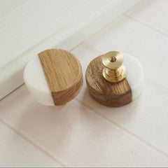 Two wooden knobs with white on a tiled floor.