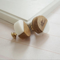 Two wooden knobs with white on a white surface.