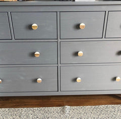 Gray dresser with wooden knobs and white knobs on a dresser.