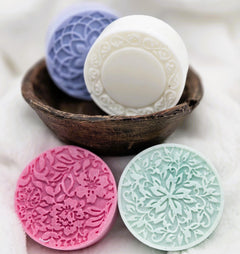 Decorative soaps with intricate patterns in a wooden bowl on a light background