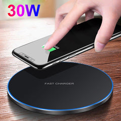 Hand placing a smartphone on a wireless charger with '30W' text, on a wooden surface.