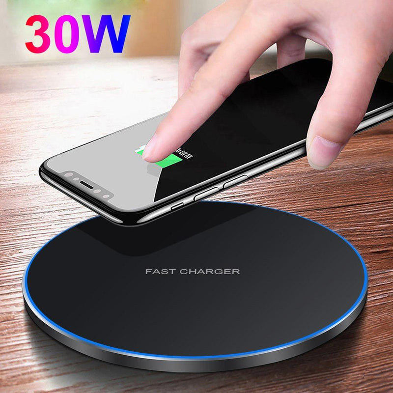 Hand placing a smartphone on a wireless charger with '30W' text, on a wooden surface.